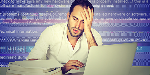 Man at computer holding head in hand